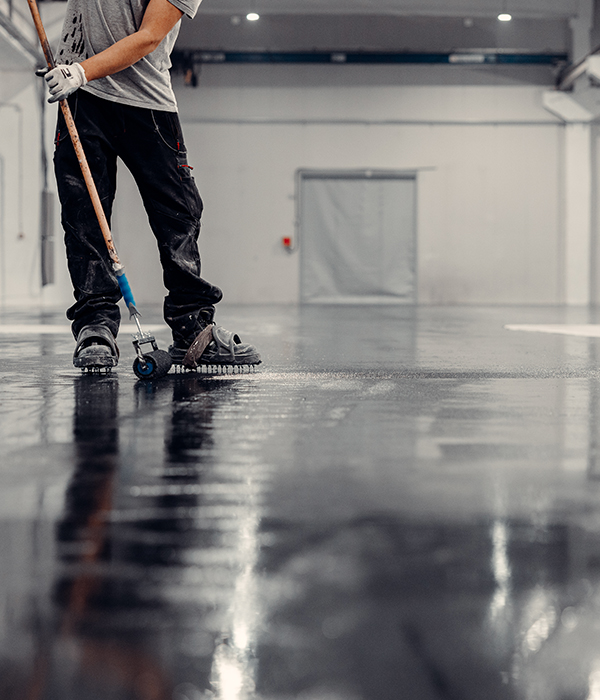 Interior view of a multi-car garage featuring a decorative gray flake epoxy floor coating with a high-gloss finish.