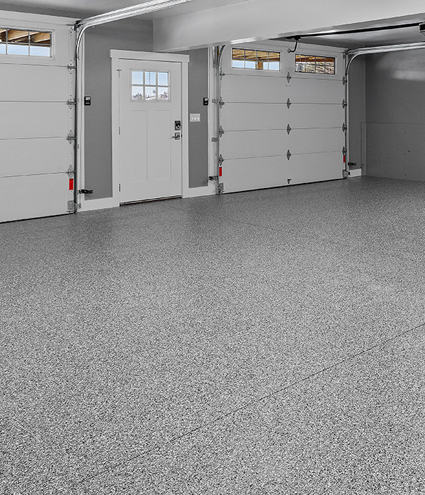 Flooring contractor applying a sleek black epoxy resin coating to a large commercial warehouse floor using a specialized roller.