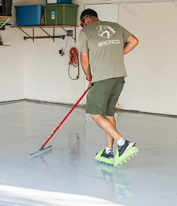 Interior view of a multi-car garage featuring a decorative gray flake epoxy floor coating with a high-gloss finish